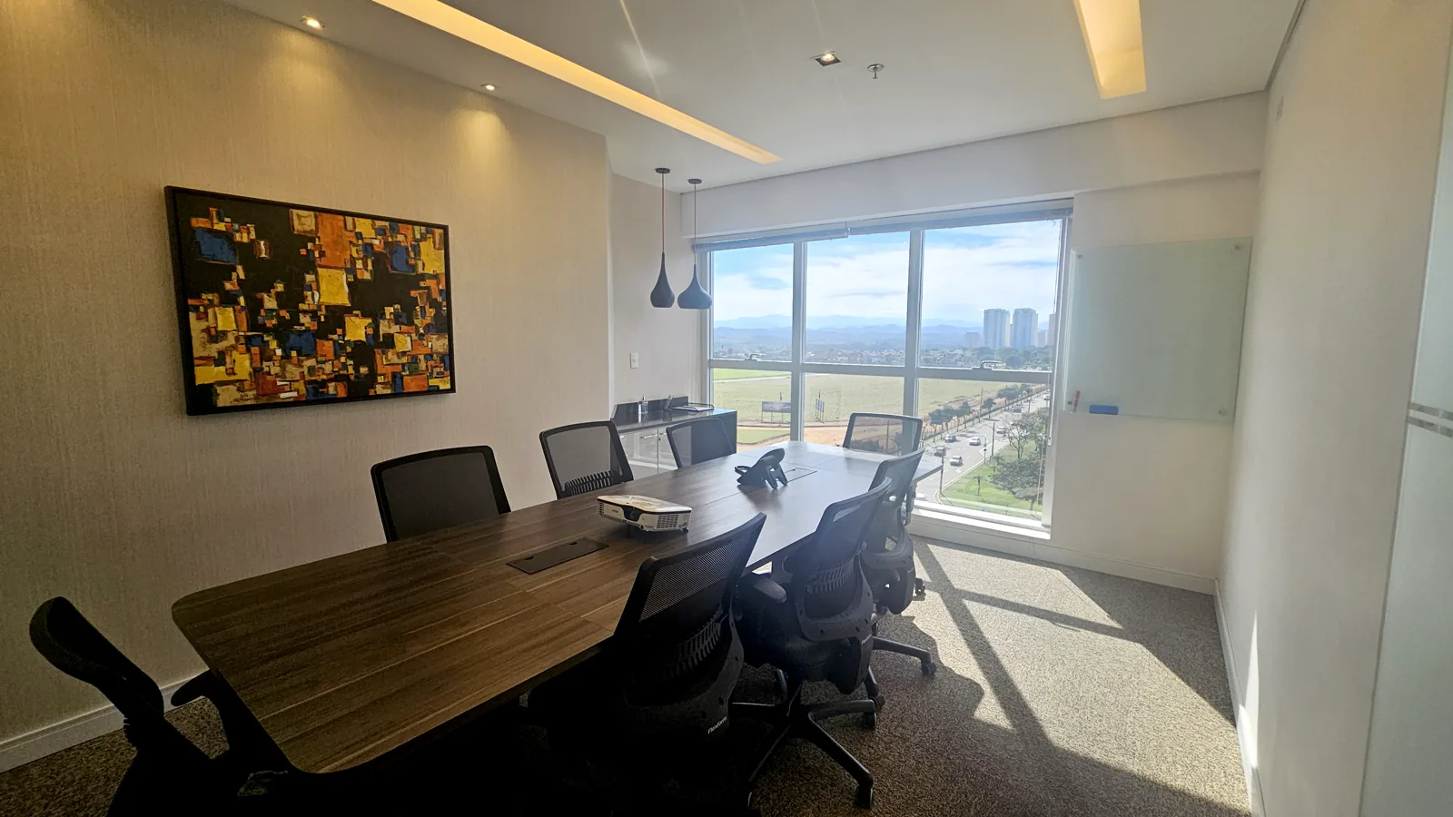 Sala de reunião com mesa para oito lugares e janela ampla